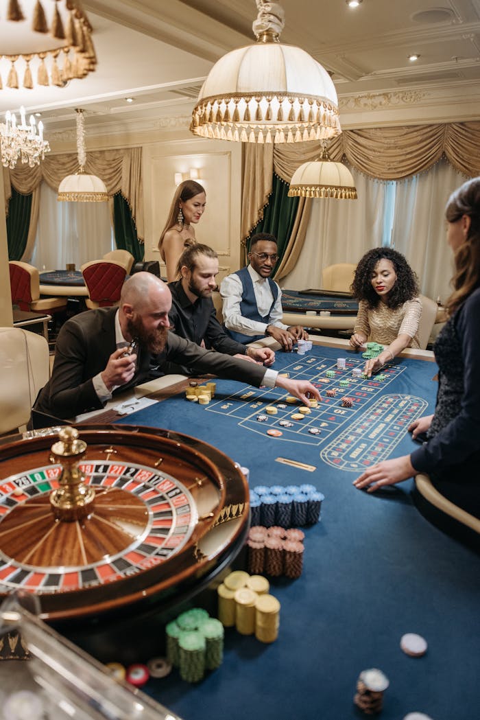 A group of diverse adults playing roulette in an upscale, indoor casino setting.
